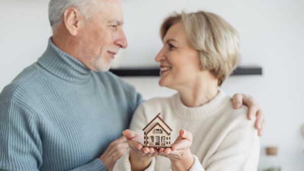 Couple standing together, while woman holding little house on hands