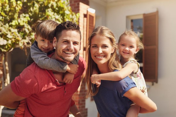 happy-couple-giving-children-piggyback-ride-outside-home