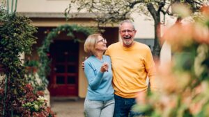 Senior couple holding keys and standing outside their new home