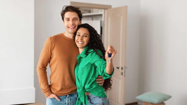 Happy couple showing keys from flat on moving day